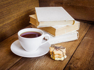 Books, cookies and cup of tea on wooden background