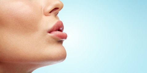close up of young woman lips over blue - obrazy, fototapety, plakaty