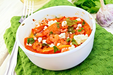 Shrimp and tomatoes with feta in white bowl on light board