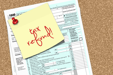note with tax refund text and 1040 tax form pinned to pin board