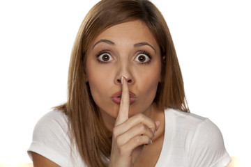 Fototapeta premium young woman with a finger on her lips - a gesture for silence