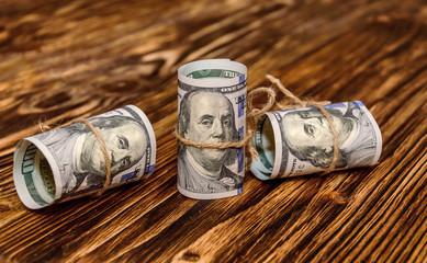 American Dollar Bills rolled up with a thread on the wooden back
