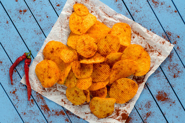 Crispy potato chips on blue wooden table