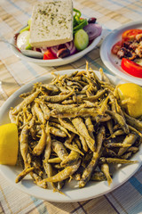 Small fried fish, chips and greek salad on the table, Greece