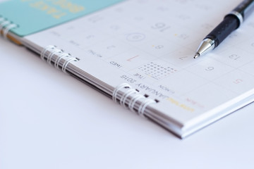 close-up sheet of a calendar and a pen on white background