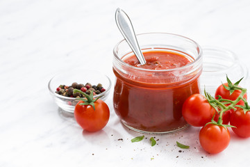 tomato sauce in a glass jar and white background, closeup