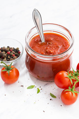 tomato sauce in glass jar on white background, vertical closeup