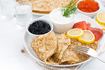 traditional Russian crepes with caviar and salted fish on table