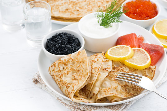 traditional Russian crepes with caviar and salted fish on table