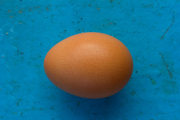Brown chicken egg in shell on an old blue background. Top view closeup. Shallow depth of field