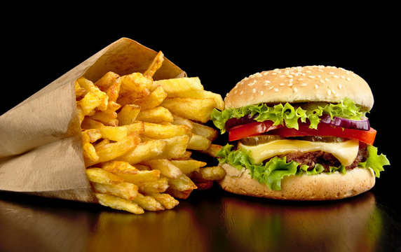 Big cheeseburger with french fries on black board