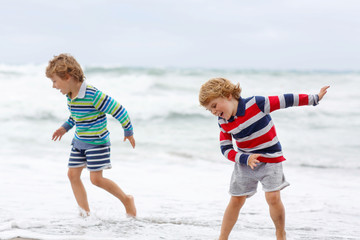 Two kid boys playing on beach on stormy day