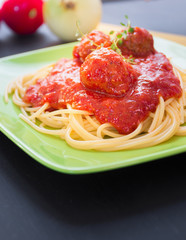 Spaghetti pasta with meatballs and tomato sauce, on black backgr