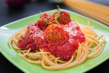 Spaghetti pasta with meatballs and tomato sauce, on black backgr