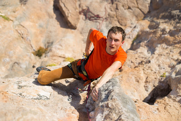 Young man climbing on a limestone wall with wide valley on the background