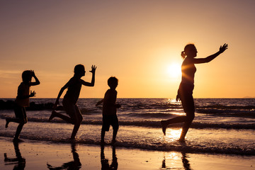 Fototapeta premium Mother and children playing on the beach at the sunset time.