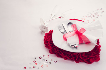 piatto e posate con cuore di san valentino e flute su un piano bianco