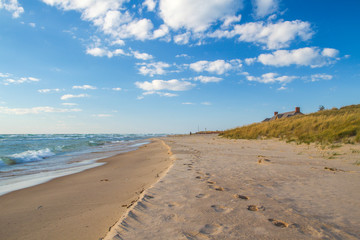 Coastal Living. Wide sandy beach with roof of the Ludington State Park beach house at the horizon. Ludington, Michigan.