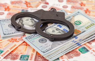 Steel handcuffs lying on a stack of dollar bills on the backgrou