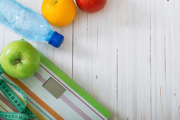 Scales, fruits, water on the white wooden background