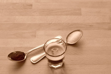 caffe a casa, espresso in un bicchierino di vetro con due cucchiaini, uno di zucchero e uno di caffe macinato, vintage, tono seppia