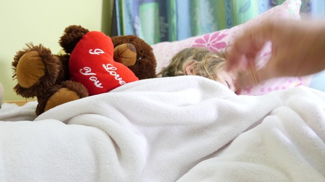 p&egrave;re recouvrant sa fille avec une couverture pendant son sommeil