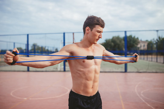 strong athletic guy sports man stretches expander