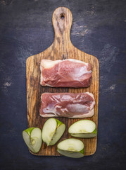 raw duck breast with cinnamon, cloves and sliced apples on a cutting board