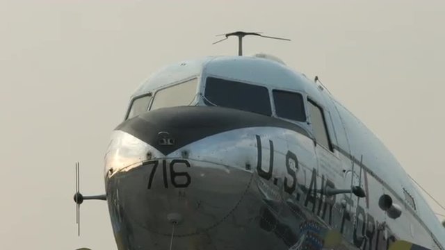 Pan to the cockpit of a Douglas C-47 Skytrain historic military transport plane, parked at dawn at an airfield.  Also known as the Dakota in the UK.  Recorded in 4K, ultra high definition.