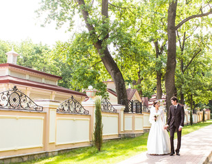 Bride and groom walking away in summer park outdoors