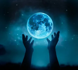 Fototapete Vollmond Abstract hands while praying at blue full moon with star in dark background