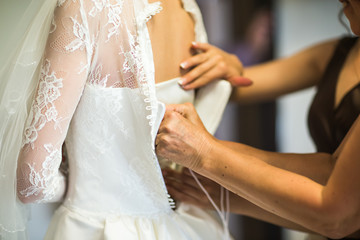 Obraz na płótnie Canvas Brides maid helps bride in wedding dress 