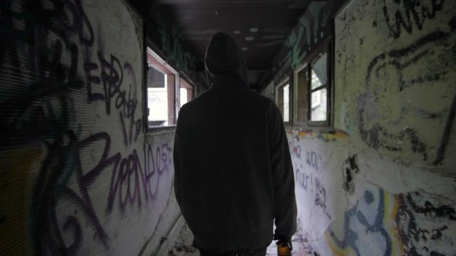 Slow motion of a bum walking in an abandoned house