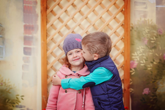 Little boy kissing smiling little girl on her cheek, outdoor por
