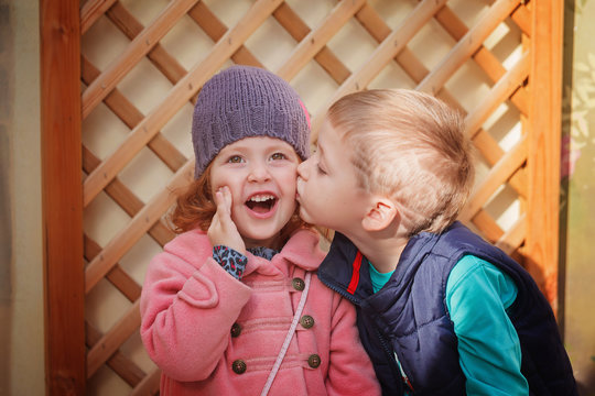 Little boy kissing smiling little girl  in sunny day. Valentine