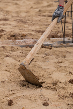 Digging The Soil With A Hoe At Construction