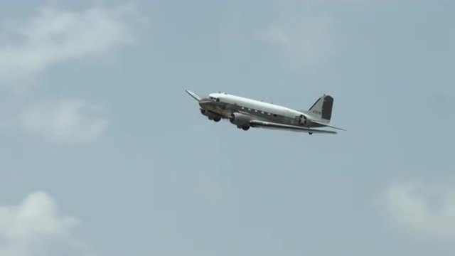 Douglas C-47 Skytrain historic military transport plane flying in cloudy sky.  Also known as the Dakota in the UK.  Recorded in 4K, ultra high definition.