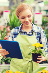 happy woman with tablet pc in greenhouse