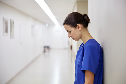 sad female nurse at hospital corridor