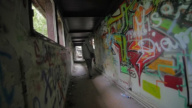 Slow motion of guy with bottle walking through abandoned building