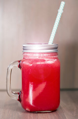 Watermelon smoothie in a mason jar on wooden background
