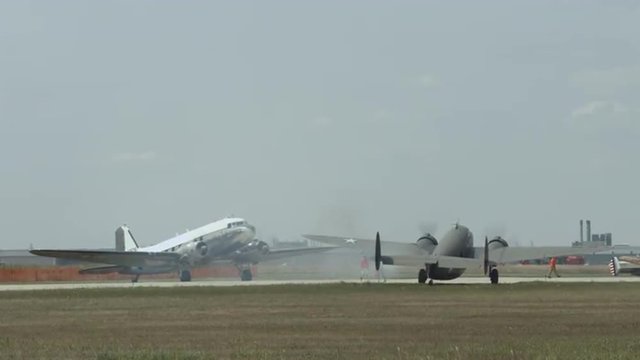 Douglas C-47 Skytrain historic military transport and B-25 Mitchell bomber wait on taxiway at airfield.  Recorded in 4K, ultra high definition.