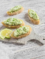 Toast with avocado and cream cheese on a white board. Healthy food. Delicious breakfast or snack