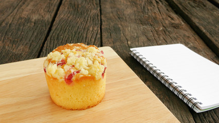 The delicious blueberry muffin and small note book on the old deep brown planks.