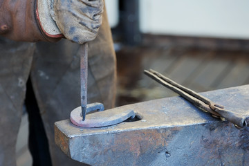 Blacksmith forges a horseshoe