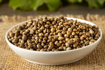 A white ceramic bowl full of hemp seeds, close up