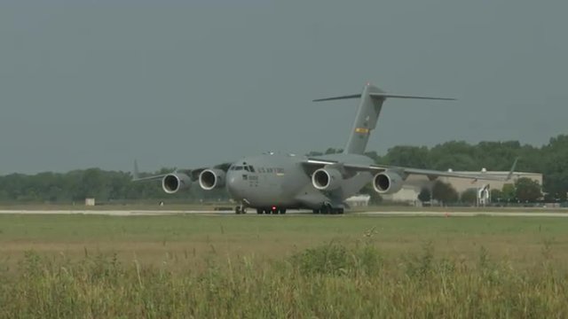 Boeing C-17 Globemaster military transport plane turns toward camera while taxiing at airfield. Used by the United States Air Force and developed by McDonnell Douglas.