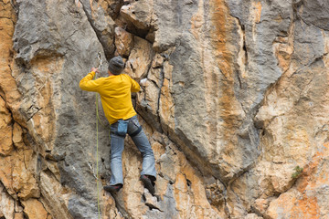 Fototapeta premium Young male climber hanging on a cliff with a rope.