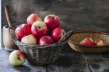 Old basket with apples on wooden background