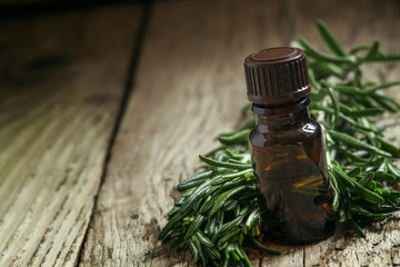 Rosemary essential oil in a small bottle and fresh rosemary on a